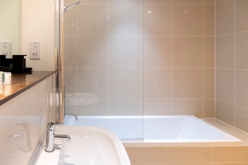 Modern bathroom with bathtub, glass shower enclosure, sink and tiled walls