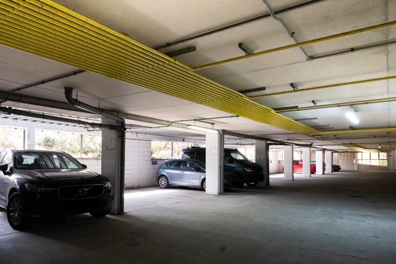 Underground parking garage with parked cars, concrete floor and yellow ceiling beam