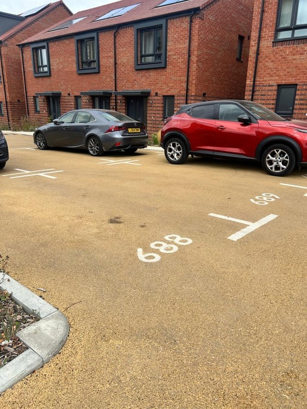 Brick residential building with parking area showing two parked cars