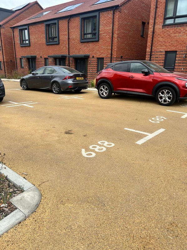 Brick apartment building exterior with parking area and two parked cars