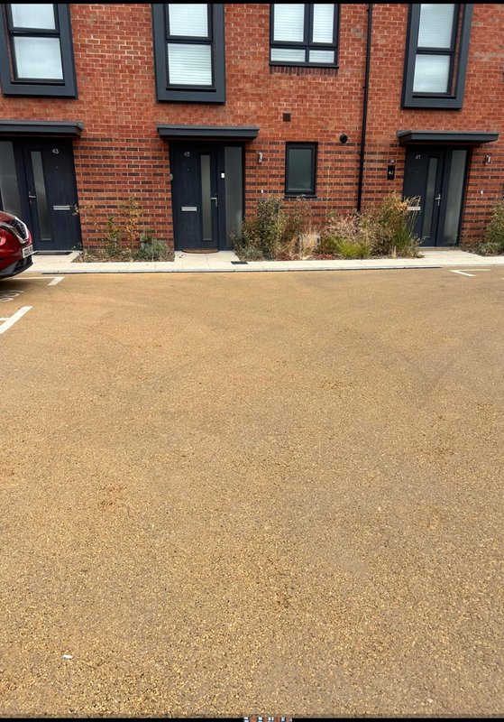 Brick building exterior with black doors, windows, and gravel driveway forecourt