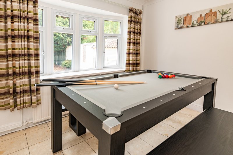 Recreation room with pool table, checkered curtains, and large windows overlooking garden