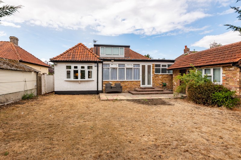 Single-story brick bungalow with tiled roof, driveway and front garden