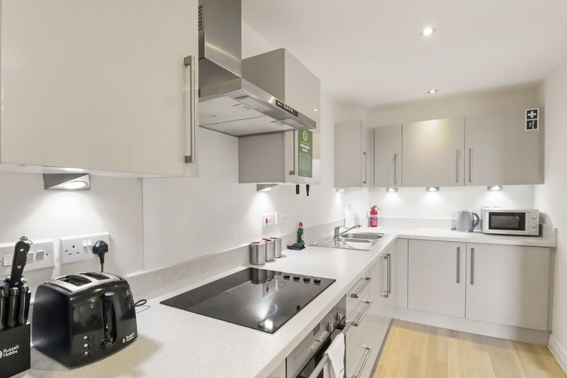 Modern white kitchen with island cooktop, stainless steel hood, and integrated appliances