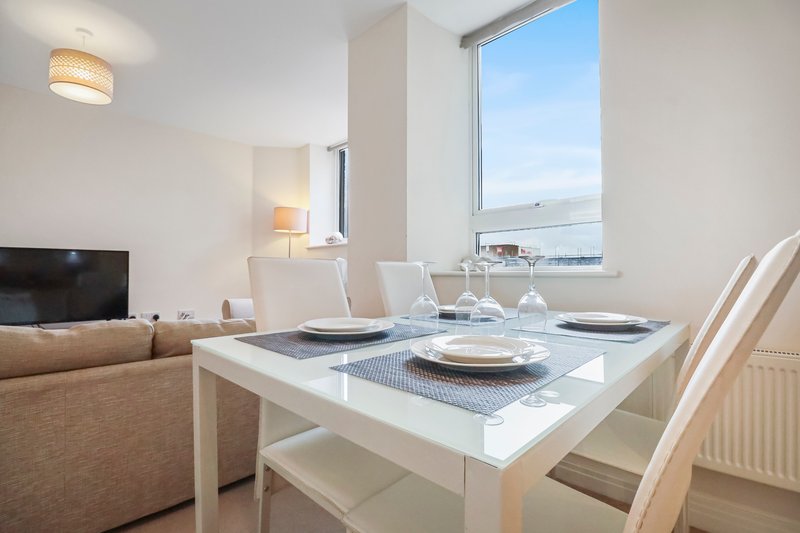Modern dining table with place settings overlooking water view through large window