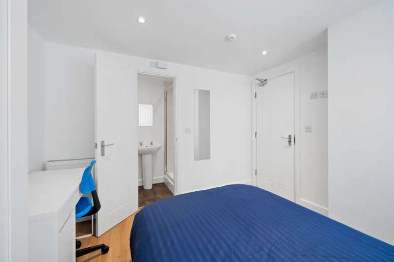 Modern bedroom with double bed, ensuite bathroom, wooden floor and white walls