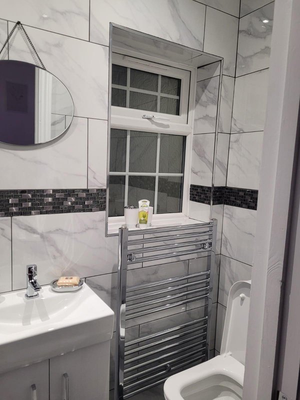 Modern bathroom with marble tiles, heated towel rail, sink and toilet