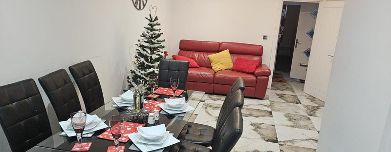 Living and dining area with red sofa, dining table, chairs, and Christmas decorations