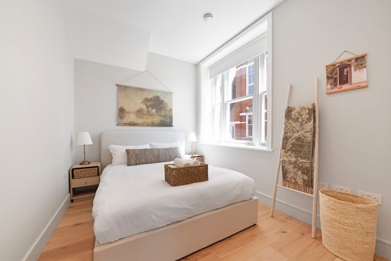 Bright bedroom with double bed, wooden floor, bedside table and window with city view