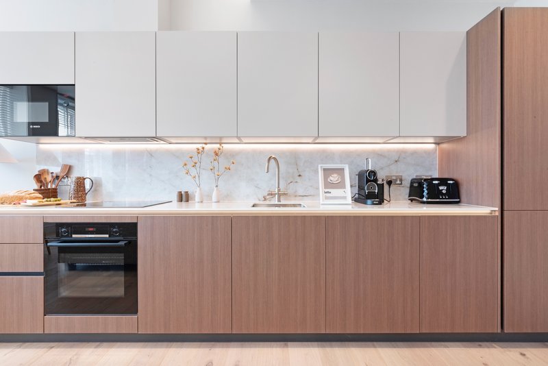 Modern kitchen with white upper cabinets, wooden lower cabinets, marble backsplash and stainless steel appliances