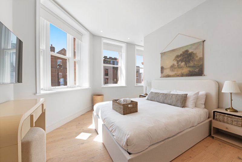 Bright bedroom with double bed, wooden floor, large windows and city views