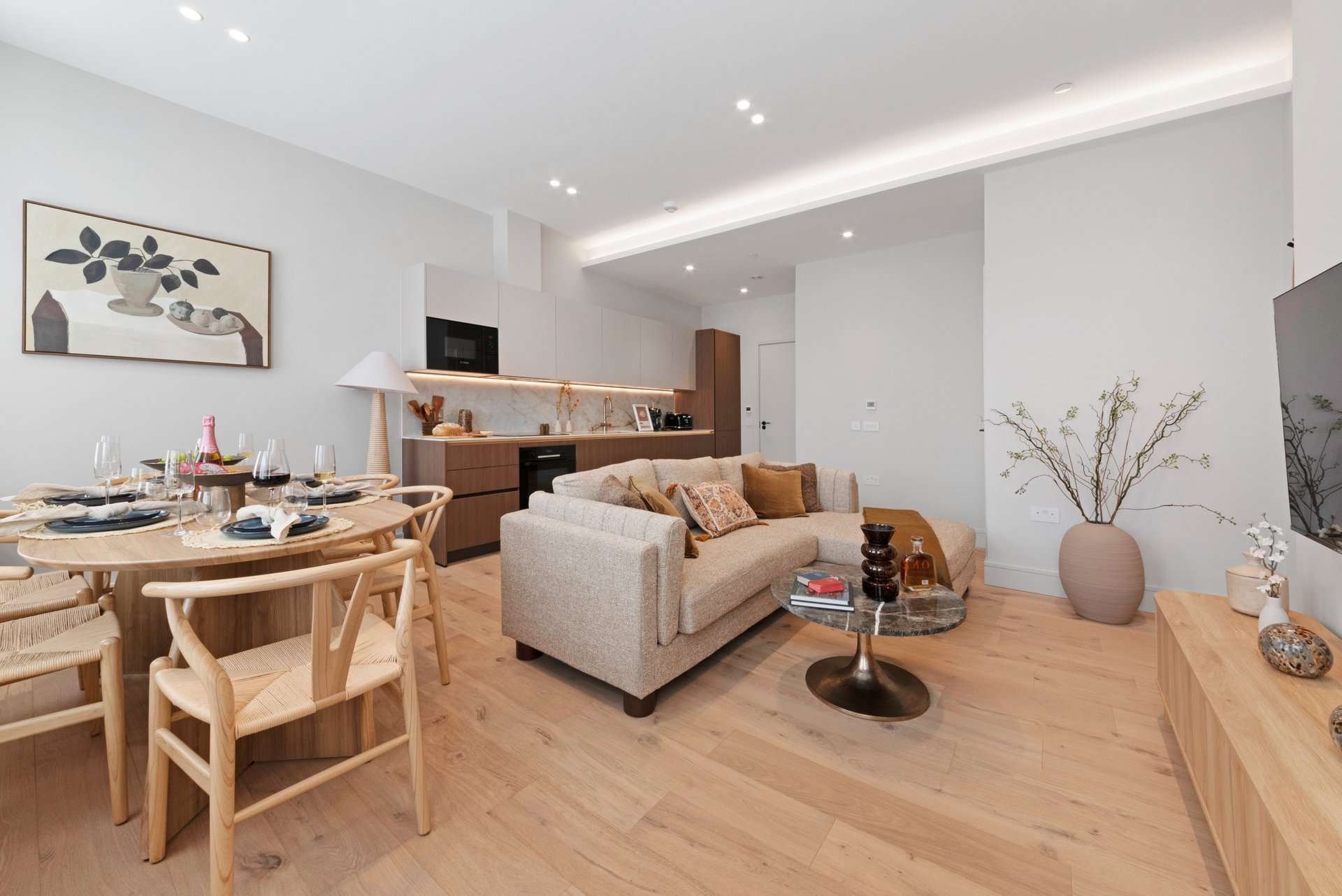Open-plan living space with dining table, sofa, kitchen and wooden flooring