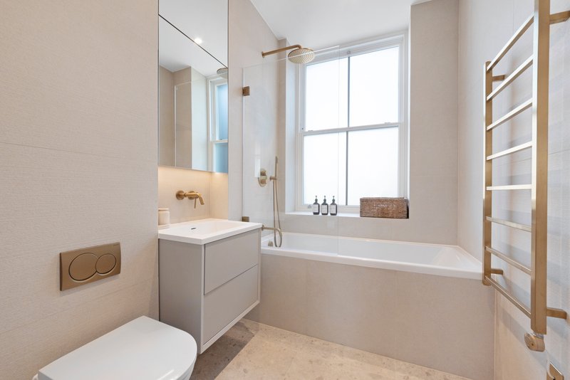 Modern bathroom with white toilet, vanity sink, bathtub, heated towel rail and large window