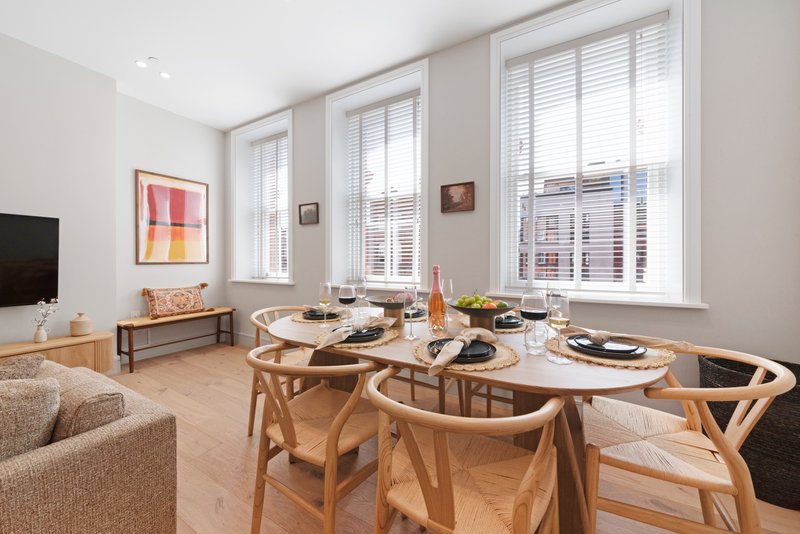 Modern dining area with wooden table, chairs, and place settings near large windows