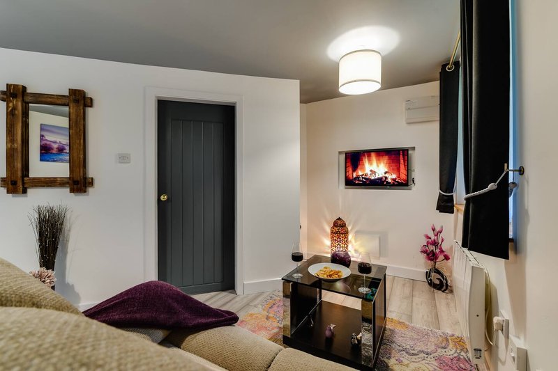 Compact bedroom with double bed, fireplace wall art, black door and decorative furnishings