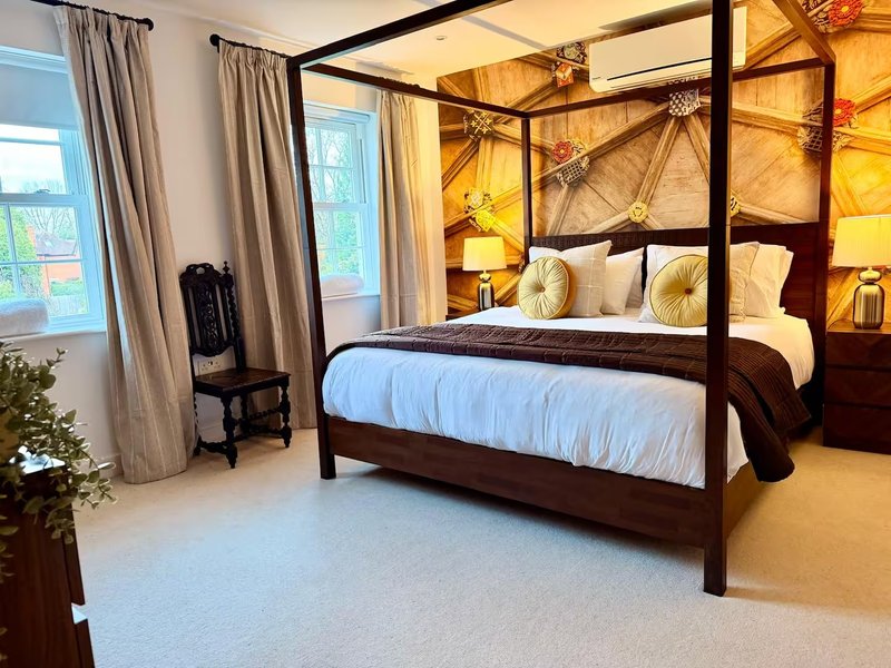 Luxury bedroom with four-poster bed, gold accent lighting, cream carpet and curtains