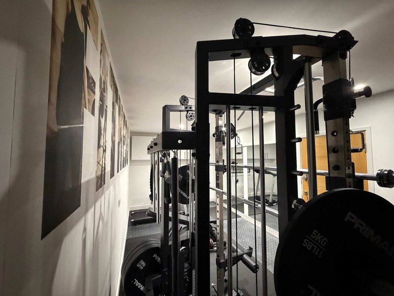 Home gym with weight rack, dumbbells, and exercise equipment in white room
