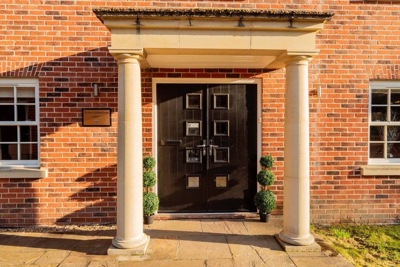 Red brick house exterior with dark wooden door, white columns, and stone porch entrance