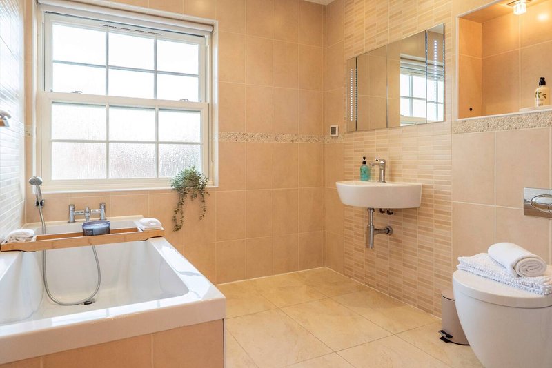 Spacious bathroom with bathtub, walk-in shower, sink, toilet and large window