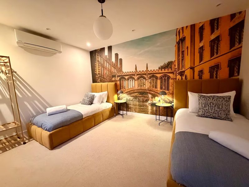 Modern bedroom with two single beds, mustard upholstery, architectural mural, and pendant light