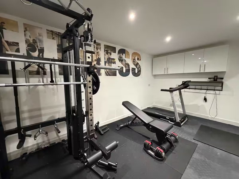 Home gym with treadmill, dumbbells, weight bench and exercise equipment