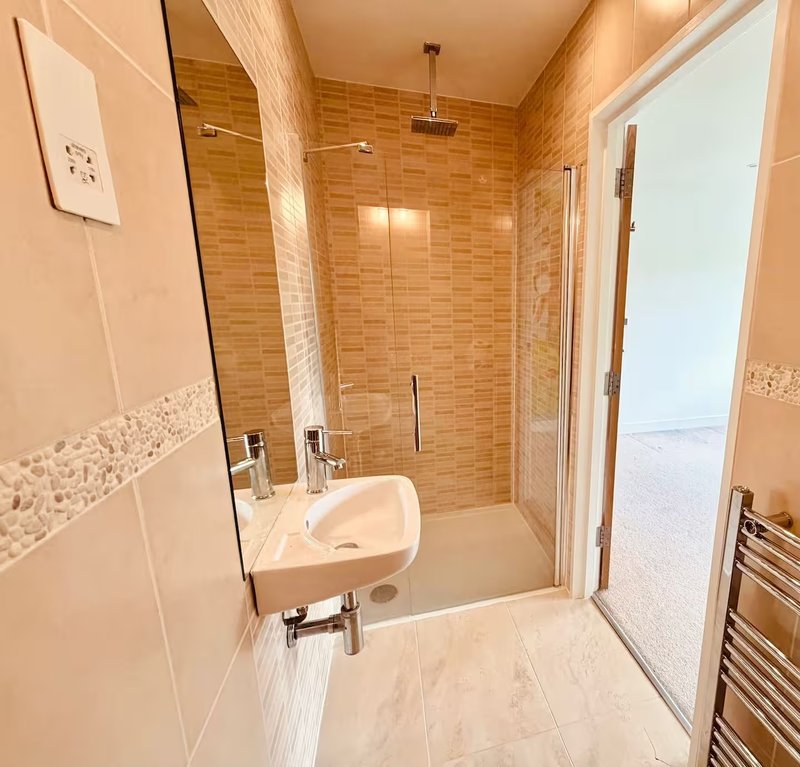 Modern bathroom with walk-in shower, wall-mounted sink, and heated towel rail