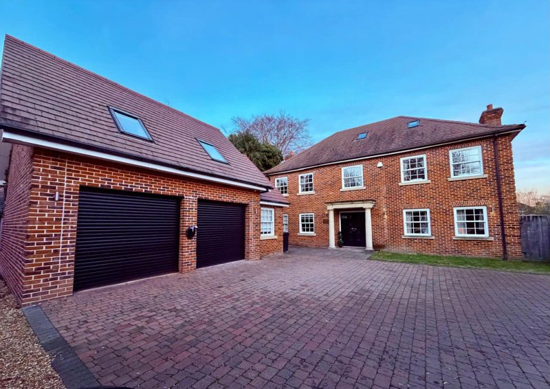 Brick-built residential property with double garage, driveway, and landscaped grounds