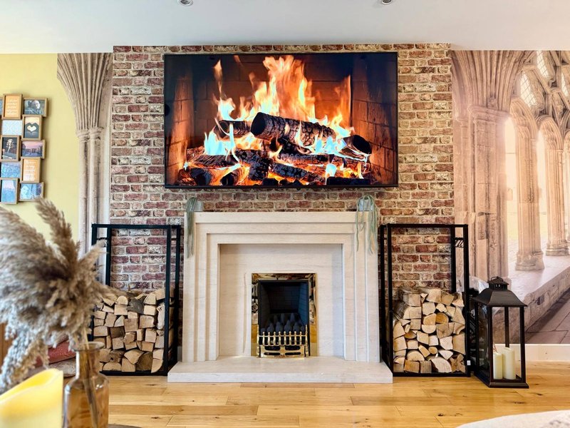 Fireplace with brick surround, white mantelpiece, and wood storage baskets on either side