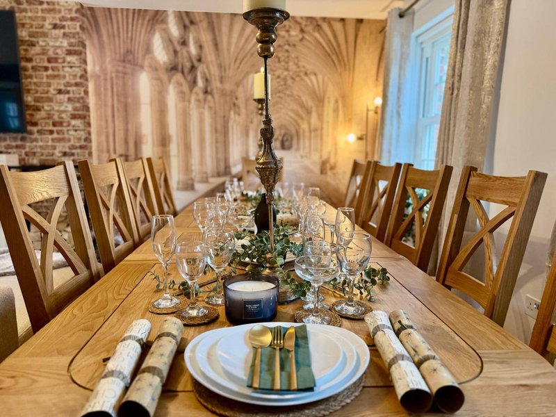 Formal dining room with wooden table, place settings, and hanging pendant lamp