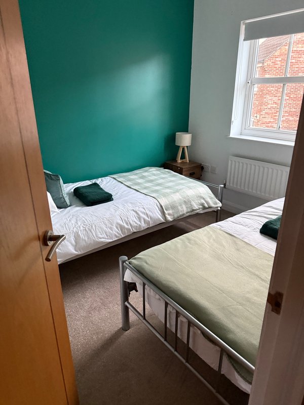 Shared bedroom with two single beds, teal accent wall, window with brick view