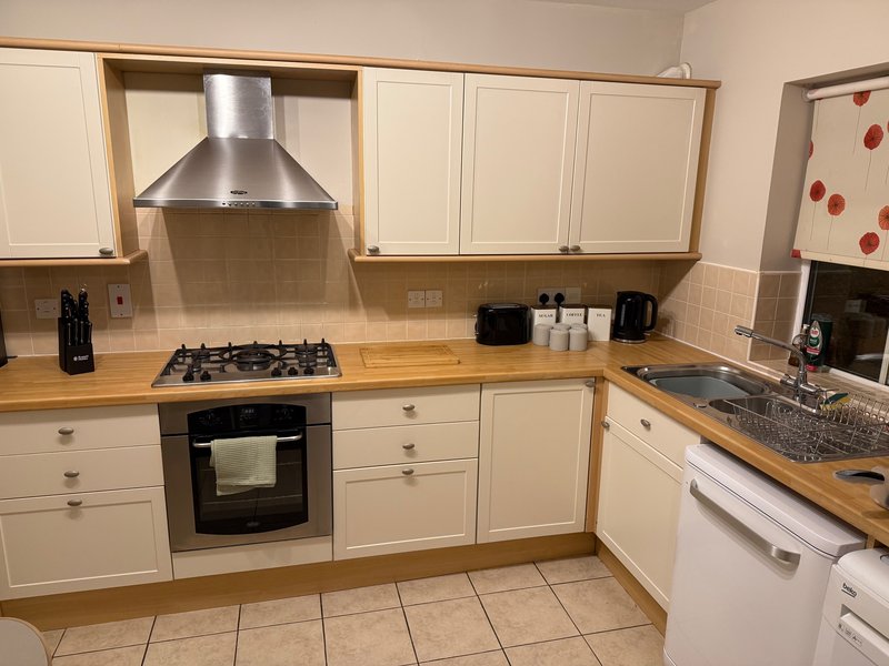 Modern kitchen with white cabinets, wooden worktops, gas hob, stainless steel extractor hood