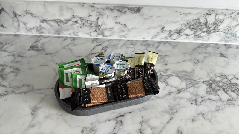 Marble bathroom counter with assorted toiletries and branded products in black organizer tray