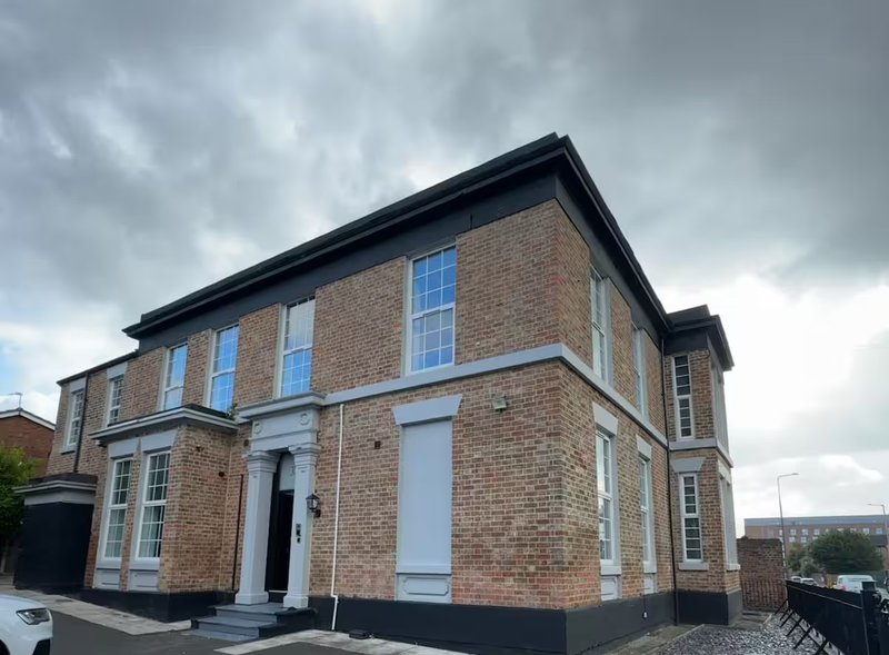 Brick Victorian house with black roof, white-framed windows and white entrance door
