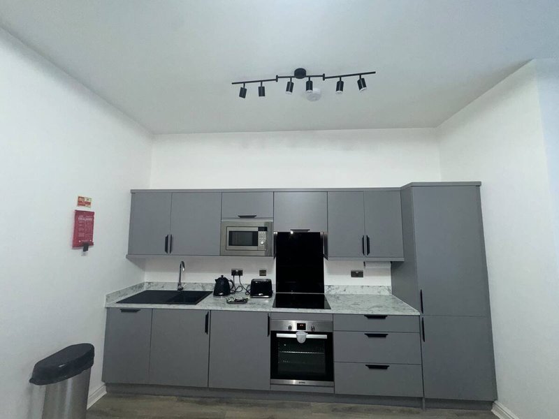 Modern kitchen with gray cabinetry, white countertop, built-in appliances and track lighting
