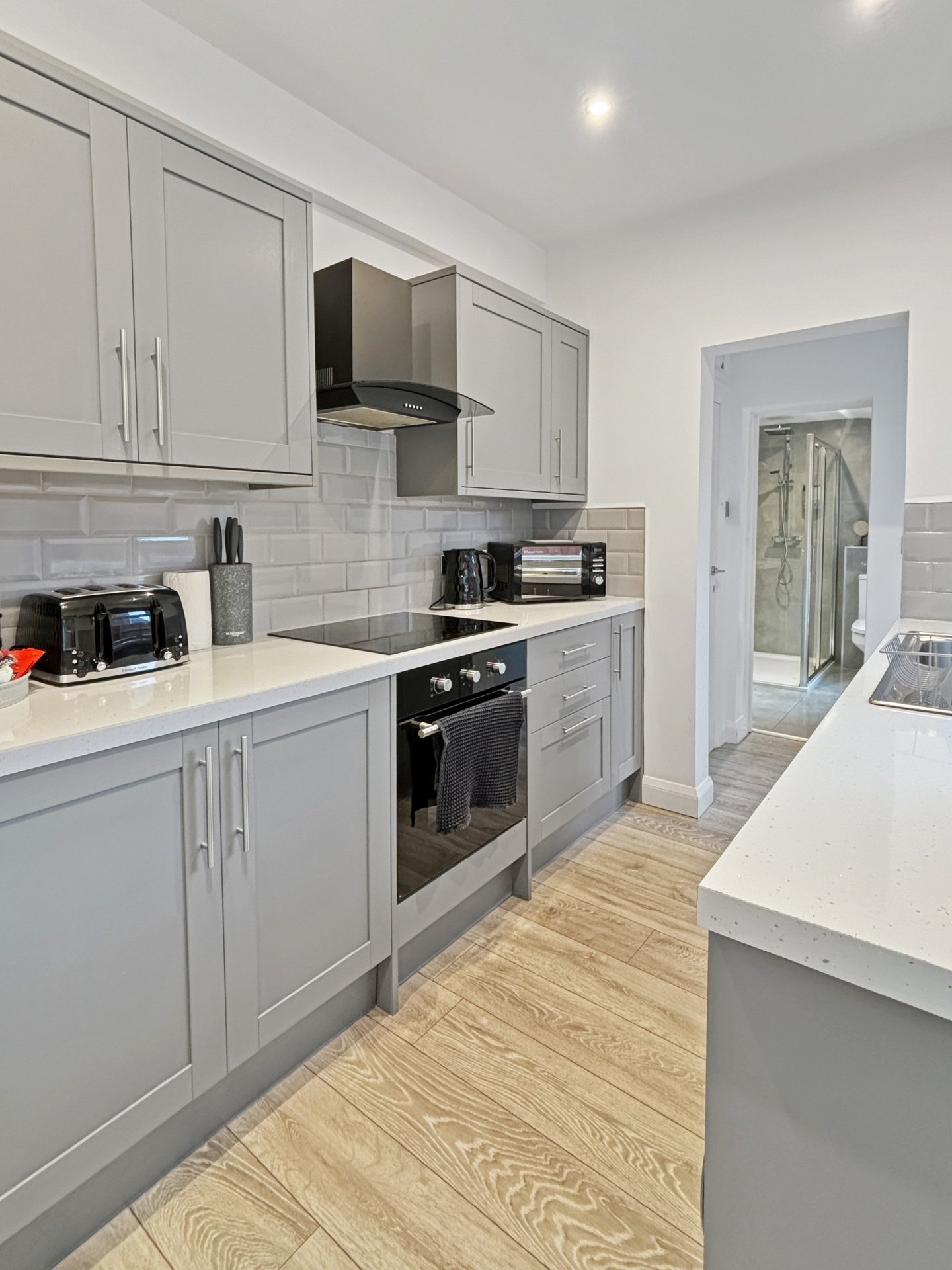 Modern kitchen with grey cabinetry, stainless steel appliances, white subway tile backsplash and wooden flooring