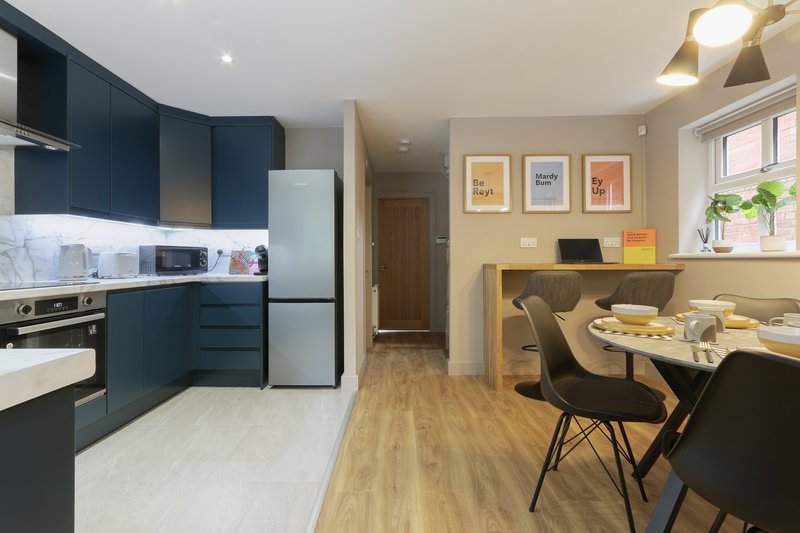 Open-plan kitchen and dining area with dark blue cabinetry, dining table, and framed wall art