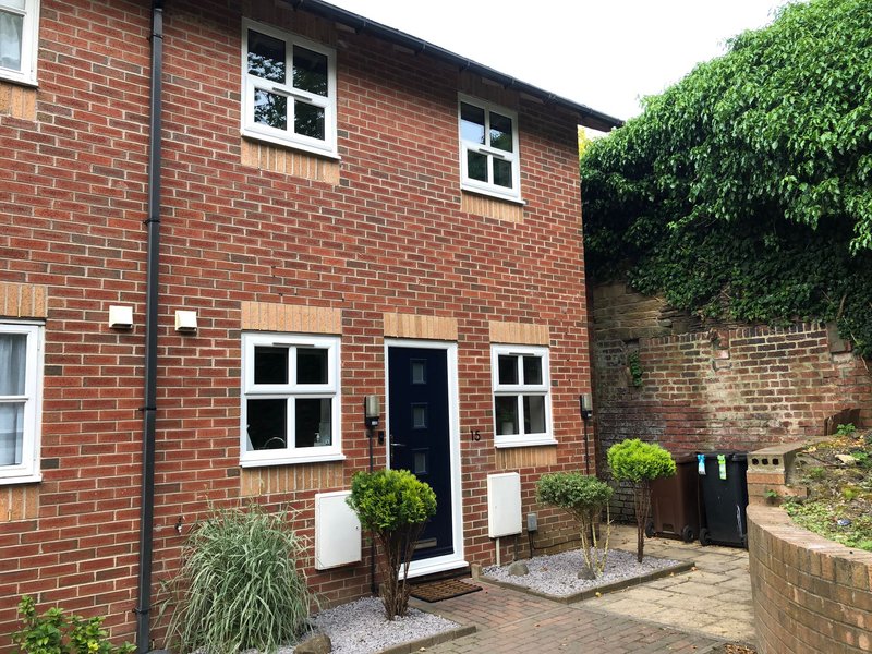 Red brick terraced house with front door, white-framed windows and ivy-covered wall