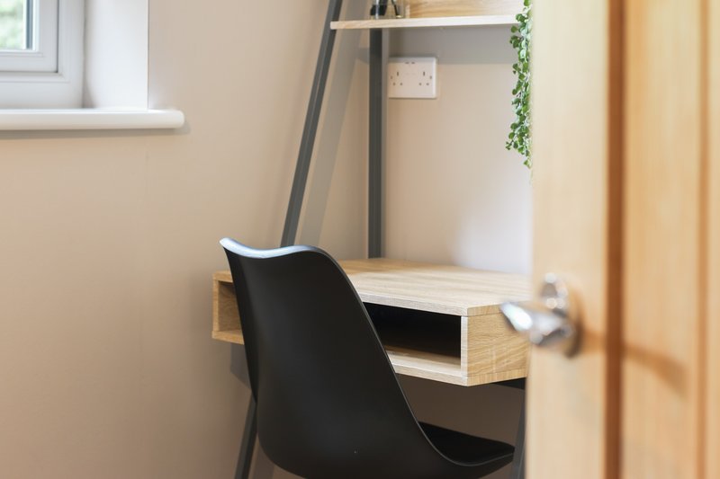 Compact home office workspace with black chair, wooden desk and shelving unit
