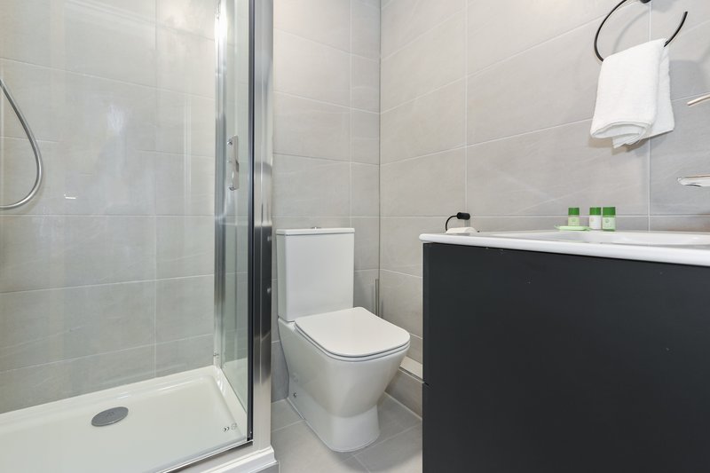 Modern bathroom with shower enclosure, toilet, black vanity and white towel rail
