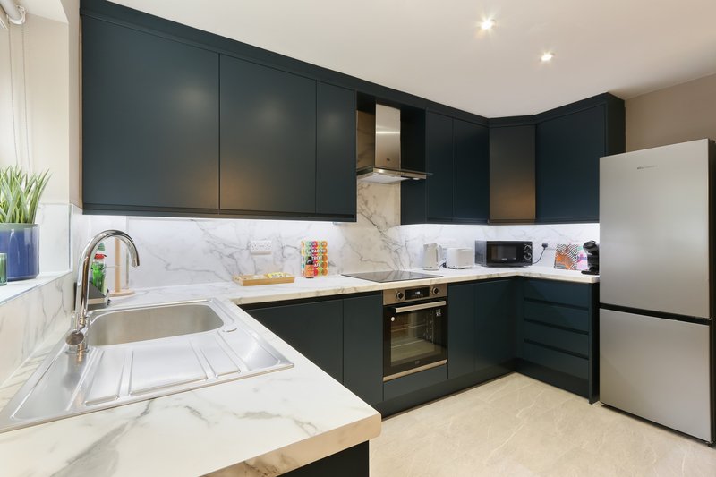 Modern kitchen with black cabinetry, white marble countertops and backsplash, stainless steel appliances