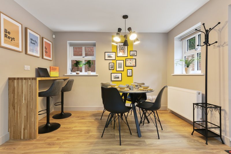 Modern home office and dining space with desk, wooden flooring, wall art, and dining table with chairs