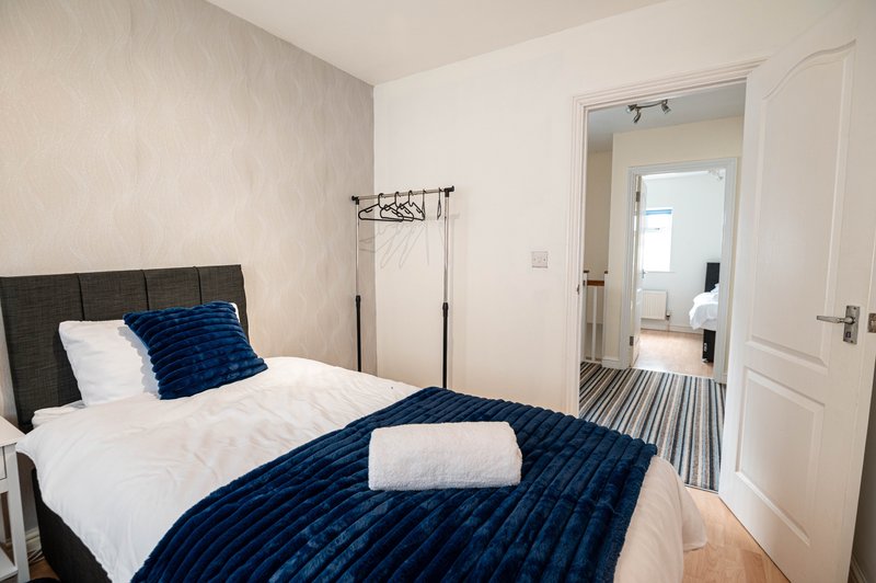 Bedroom with double bed, blue bedding, black headboard, and open door to ensuite