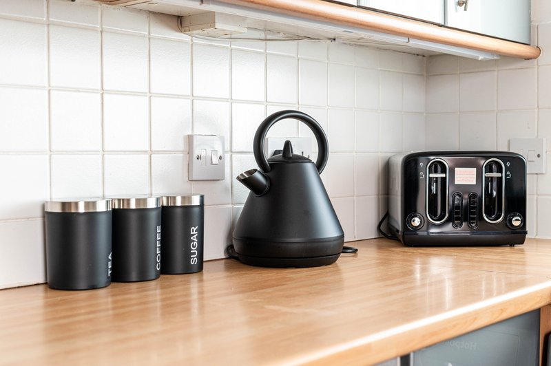Kitchen counter with kettle, toaster, and black canisters beside white tile backsplash