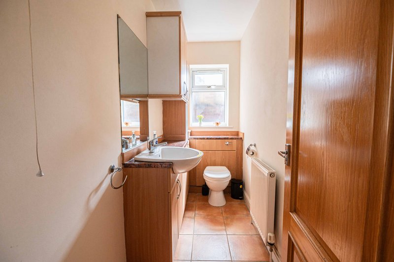 Bathroom with wooden vanity, mirror, toilet, and window overlooking garden