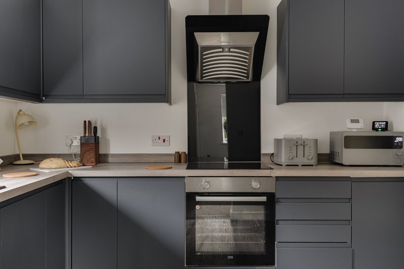 Modern kitchen with dark grey cabinets, integrated oven, and stainless steel appliances