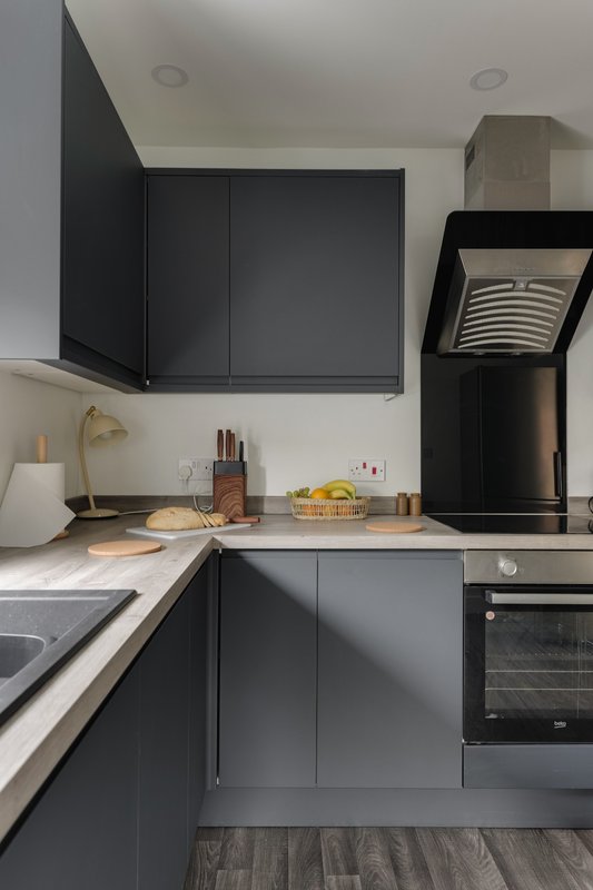 Modern kitchen with dark cabinetry, white countertop, stainless steel appliances and coffee maker