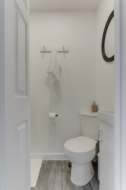 Small bathroom with white toilet, sink, towel rail and curved mirror on wall