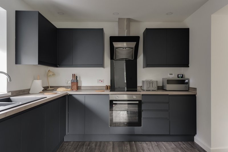 Modern kitchen with black cabinetry, stainless steel appliances, and white countertops