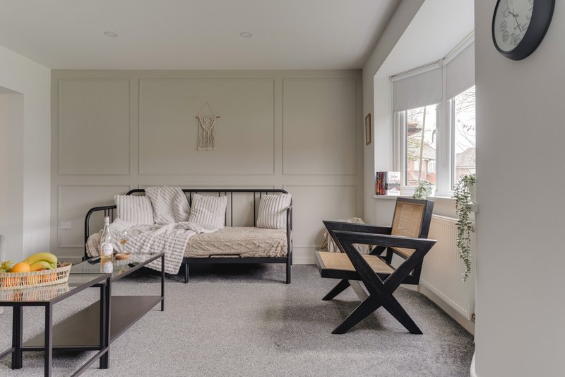 Bright bedroom with metal-frame daybed, desk, side table and window with natural light