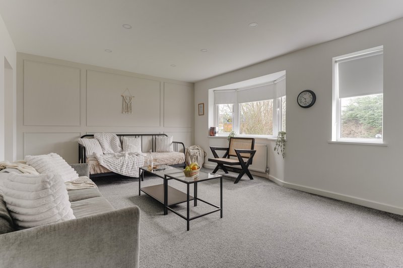 Bright modern living room with sofa, daybed, coffee table and large windows